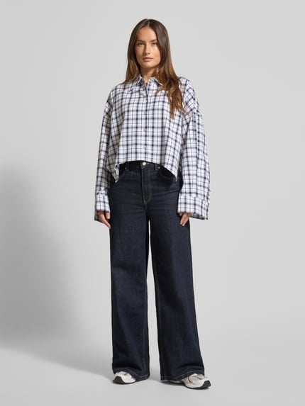 Vrouwenmodel draagt Oversized Hemdblouse met Knopsluiting Model 'OSHIA' van Drykorn, puur katoen, overhemdkraag, witte en blauwe ruiten, Ganzkörperansicht van voren.