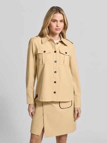 Frauenmodel trägt Longline Langarmbluse mit Schulterklappen von BAUM & PFERDGARTEN, beige, Struktur, Regular Fit, Ganzkörperansicht von vorne.