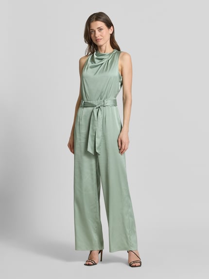 Frauenmodel trägt Jumpsuit aus Satin im ärmellosen Design von comma in zartem Mintgrün mit Stoffband und weitem Bein, Ganzkörperansicht von vorne. Taillierte Passform, Nahtreißverschluss, Rückenlänge 35 cm, Brustweite 45 cm, Gesamtlänge 110 cm, Innenbeinlänge 80 cm.