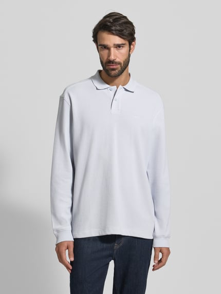Männermodel draagt Regular Fit Poloshirt aus Baumwoll-Mix Modell 'PETEMPESTOLONG' von BOSS Orange, unifarben, piqué, voorkant borstlabel, jeans, Ganzkörperansicht von vorne.
