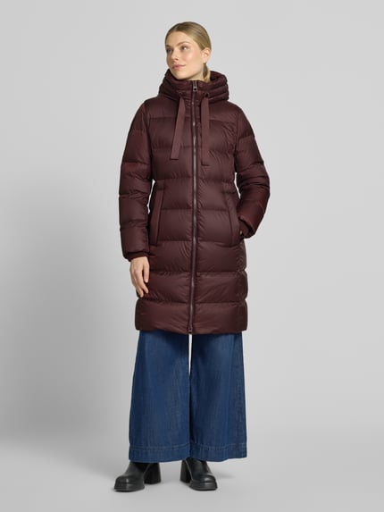 Frauenmodel trägt Regular Fit Daunenmantel mit Label-Print von Marc O'Polo in dunklem Rot, glatte Oberflächen, Ganzkörperansicht von vorne. Damen Daunenmantel von Marc O'Polo.