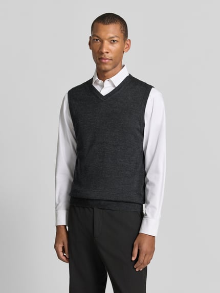 Männermodel trägt Slim Fit Pullunder aus Baumwoll-Mix mit V-Ausschnitt von Christian Berg Men, Strick-Optik, dunkles Grau, Ganzkörperansicht von vorne.