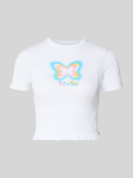 Produktfoto, T-Shirt mit Label-Print von Levi's®, weiß, reine Baumwolle, körpernahe Passform, Rüschen, Smok-Details, gerippter Rundhalsausschnitt, farbiges Schmetterlingsmotiv