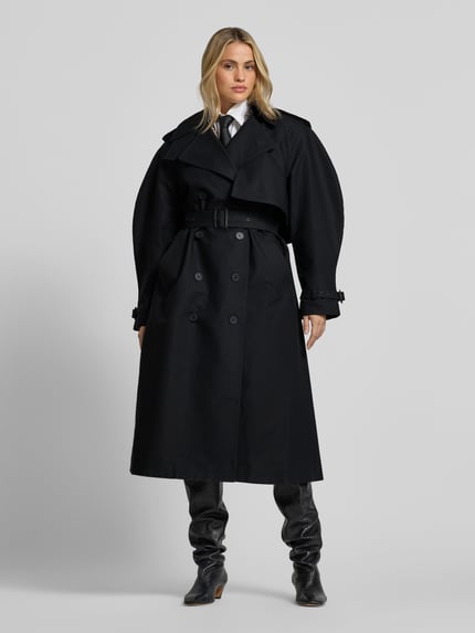 Frauenmodel trägt Trenchcoat aus reiner Baumwolle von Anine Bing, taillierte Passform, doppelte Knopfleiste, Schwarz, Ganzkörperansicht von vorne.