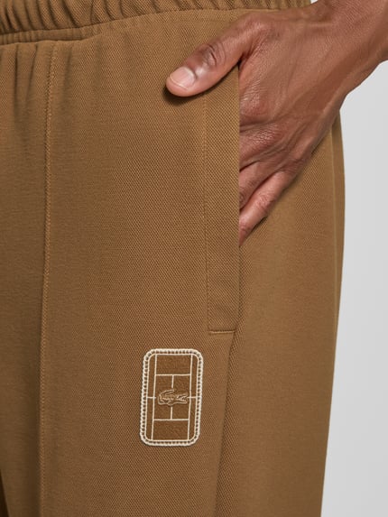 Männermodel trägt Loose fit Sweathose aus Baumwoll-Mix Modell 'Tenn' von Lacoste in Braun, sichtbare Struktur, Nahaufnahme Oberschenkel. Herren Sweathose von Lacoste