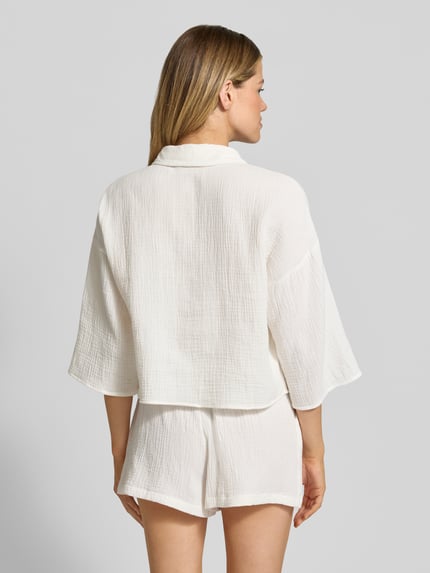 Frauenmodel trägt Loose Fit Hemdbluse aus reiner Baumwolle Modell 'NATALI' von Vero Moda, weiß, Seersucker, Ganzkörperansicht Rückansicht.