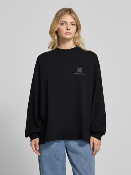 Frauenmodel trägt Oversized Longsleeve mit Logo von Karo Kauer, reine Baumwolle, Rundhalsausschnitt, schwarze Farbe, Ganzkörperansicht von vorne.