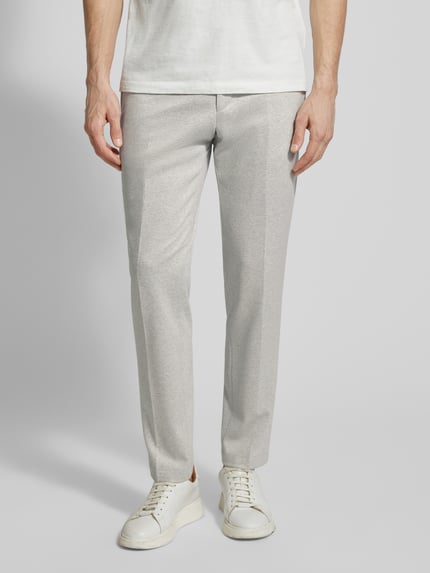 Männermodel trägt helle, gerade geschnittene Hose, glatte Textur, schlichte Form, Nahaufnahme Beinbereich, neutrale Umgebung.