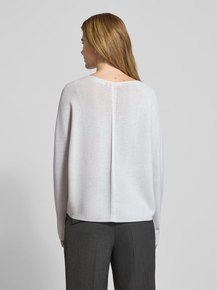 Frauenmodel trägt Schimmernder Strickpullover aus Woll-Mix von Rich & Royal, schimmernde, helle Oberfläche, Regular-Fit, Rückenlänge 56 cm, Ärmellänge 56 cm, Viskose-Anteil, Rundhalsausschnitt, Ganzkörperansicht Rückansicht.