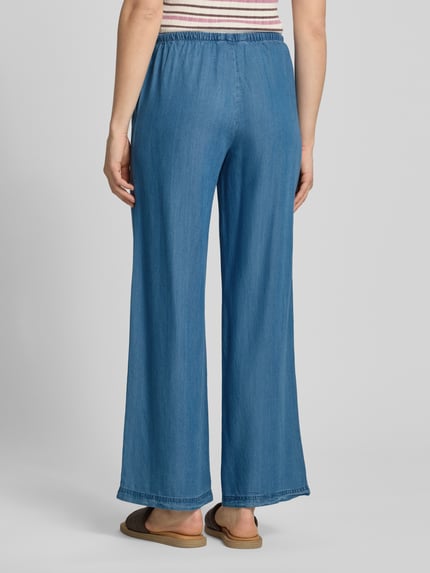 Frauenmodel trägt Wide Leg Hose aus Lyocell Modell 'CHARIS' von Only in Denim-Optik mit elastischem Bund und Eingrifftaschen, Ganzkörperansicht Rückansicht.