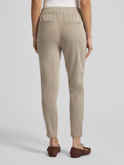 Vrouwenmodel draagt beige slim fit stoffen broek van katoenmix, elastische band en paspelzakken, Slim Fit Stoffhose mit elastischem Bund Modell 'Kate' van ICHI, binnenbeenlengte 71 cm, bandwijdte 39 cm, ganzlichaamsaanzicht achteraan.