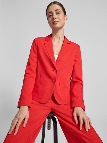 Kobiece modelka nosi Slim Fit Blazer mit Reverskragen von More & More, mieszanka materiałów z dodatkiem wiskozy, krój slim fit, kołnierz z połami, listwa guzikowa, nakładane kieszenie, długość tyłu w rozmiarze 36: 55 cm, szerokość w rozmiarze 36: 40 cm, długość rękawów w rozmiarze 36: 61 cm, intensywna czerwień, gładka struktura, całkowity widok z przodu