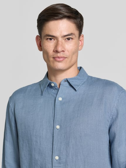 Männermodel trägt Regular Fit Leinenhemd mit Kentkragen von GAP, reine Leinen, hellblau, Knopfleiste, Nahaufnahme Oberkörper.