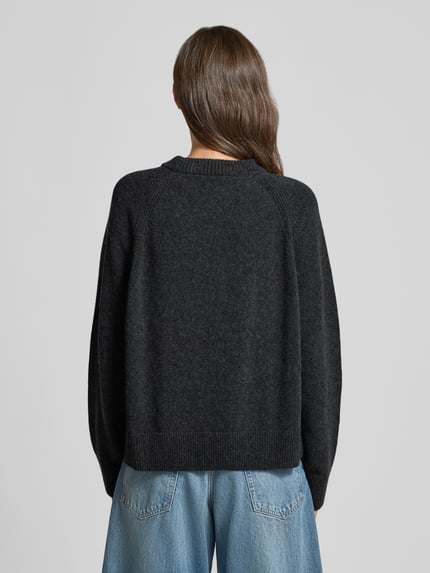 Modelka kobieca ma na sobie ciemnoszary sweter 'Loose Fit Pullover aus reiner Wolle' od ARMEDANGELS, miękka dzianina, tekstura melanż, całkowity widok z tyłu.
