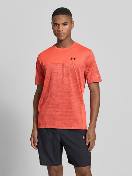 Männermodel trägt Regular Fit T-Shirt mit logo-print Modell 'Utility' van Under Armour, oranje tinten, elastisch materiaal, ronde hals, Ganzkörperansicht von vorne.