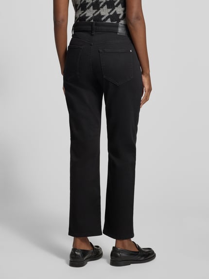 Frauenmodel trägt Regular Fit Straight Fit Jeans mit Dark Wash von BRAX in unifarbener, dunkelblauer Denim-Optik, 5-Pocket-Design, Gürtelschlaufen und Nähten, Ganzkörperansicht Rückansicht.
