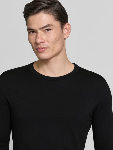 Männermodel trägt Slim Fit Pullover in Strick-Optik Modell 'Mino' von Drykorn, Reine Baumwolle, Rundhalsausschnitt, Nahaufnahme Oberkörper.