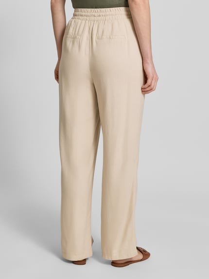 Frauenmodel trägt Loose Fit Weite Hose aus Viskose-Leinen-Mix Modell 'JESMILO' von Vero Moda, einfarbig, elastischer Bund, Ganzkörperansicht Rückansicht.