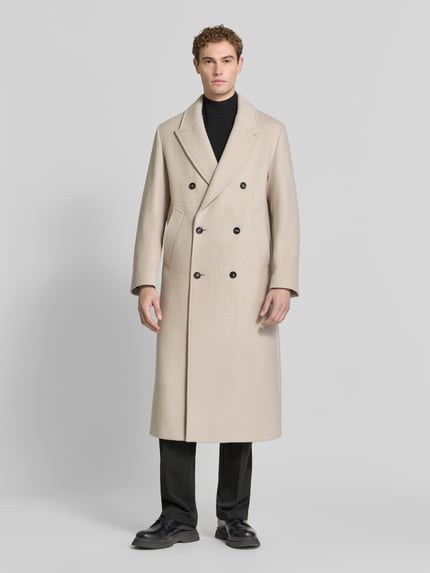 Männermodel trägt Zweireihiger Mantel aus Schurwoll-Mix mit Eingrifftaschen von bugatti, cremefarben, Knopfverschluss, Regular Fit, Ganzkörperansicht von vorne.