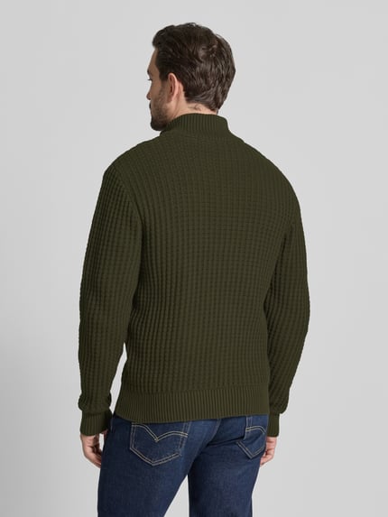 Männermodel trägt Regular Fit Troyer in Waffel-Struktur Modell 'TOM' von SELECTED HOMME, Farbe dunkelgrün, Optik: Unifarben, Passform: Regular-Fit, Applikation: Label-Patch, Kragenform: Troyer-Kragen, Verschluss: kurzer Reißverschluss, Ärmelform: Langarm, Ärmelabschluss: Gerippt, Rumpfabschluss: Gerippt, Materialverarbeitung: Strick, Material: Reine Bio-Baumwolle, Ganzkörperansicht Rückansicht.