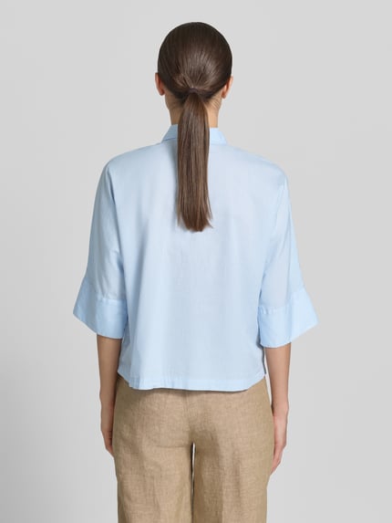 Frauenmodel trägt Boxy Fit Bluse mit 3/4-Arm von Emily Van den Bergh in Hellblau aus Reine Baumwolle mit Hemdblusenkragen und Knopfleiste, Rückenlänge 55 cm, Ärmellänge 36 cm, Ganzkörperansicht Rückansicht.