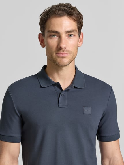 Männermodel trägt dunkelblauw regular fit poloshirt van katoenmix Regular Fit Poloshirt aus Baumwoll-Mix model 'Passenger' van BOSS Orange, Nahaufnahme Oberkörper