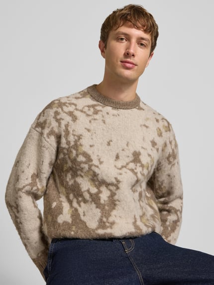 Männermodel trägt Pullover mit gerippten Abschlüssen von ONLY in mehrfarbiger Strickoptik mit abstraktem Allover-Muster, Nahaufnahme Oberkörper.