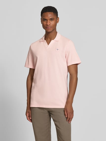 Männermodel trägt Regular Fit Poloshirt aus reiner Baumwolle von s.Oliver RED LABEL in Hellrosa, unifarben, Piqué-Struktur, Ganzkörperansicht von vorne.