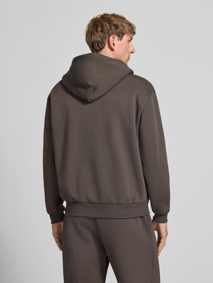 Männermodel trägt Relaxed Fit Sweatjacke aus Baumwoll-Mix mit Label-Detail von REVIEW, braun, glatte Textur, Rückenansicht, KI-modifiziertes Bild