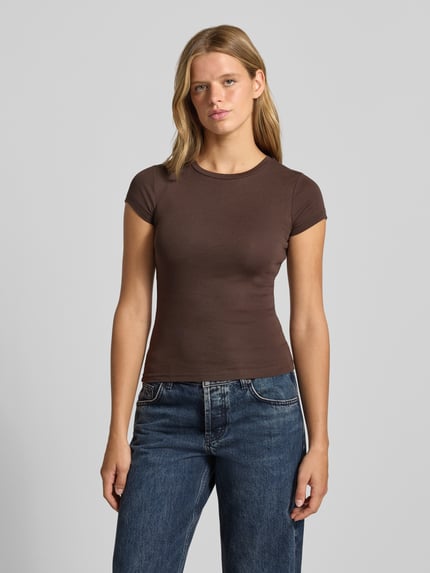 Frauenmodel trägt Skinny Fit T-Shirt aus Baumwoll-Mix von Gina Tricot in Braun, kurzärmlig, Rundhalsausschnitt, Ganzkörperansicht von vorne.