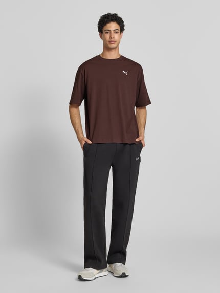 Männermodel trägt T-Shirt mit Rundhalsausschnitt von PUMA PERFORMANCE in Braun mit Logo, Reine Baumwolle, Relaxed-Fit, Rückenlänge 69 cm, Ganzkörperansicht von vorne.