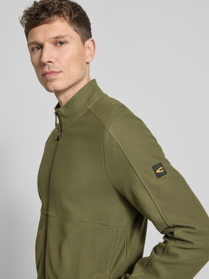 Männermodel trägt Sweatjacke mit Stehkragen und Reißverschluss von camel active in Olivgrün, reine Baumwolle, Nahaufnahme Oberkörper.