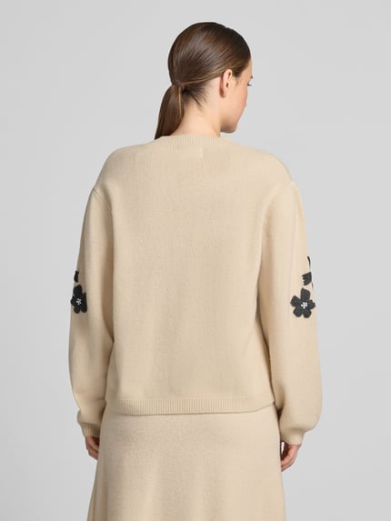 Frauenmodel trägt Strickpullover aus Wolle mit Stitchings und Perlen von Christian Berg Woman in Creme, Relaxed Fit, Rückenansicht.