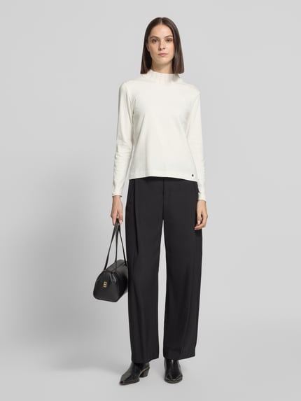 Frauenmodel trägt Langarmshirt mit Ripp Stehkragen von MARC CAIN, unifarben, Strukturmuster, schwarzer Hose, Ganzkörperansicht von vorne.