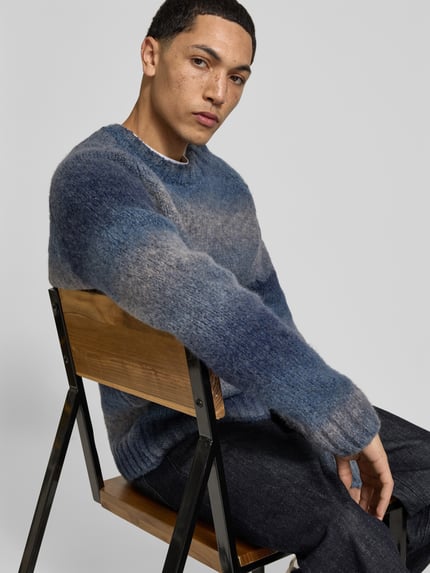Männermodel trägt Pullover aus Woll-Mix von Forét, prosty krój, okrągły dekolt, raglanowe rękawy, prążkowane wykończenia, Długość tyłu w rozmiarze M: 73 cm, widok z przodu, ujęcie bliskie od pasa w górę.