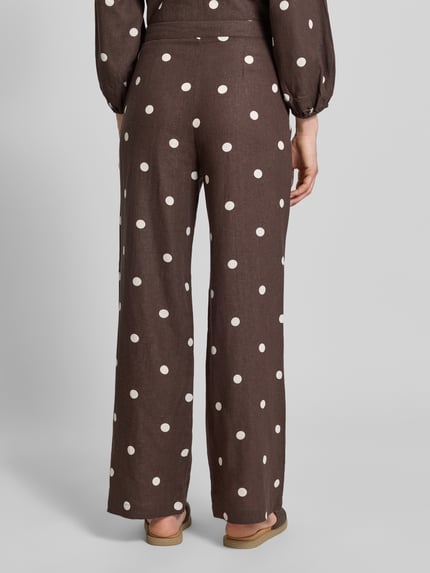 Frauenmodel trägt Stoffhose mit Schleifen-Detail von Jake*s Casual in Braun mit weißen Punkten, Lockerer-Schnitt, Ganzkörperansicht Rückansicht. Bundweite bei Größe 36: 40 cm, Innenbeinlänge bei Größe 36: 83 cm.