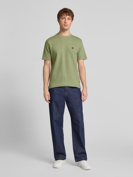 Mannmodel draagt groen T-shirt met labeldetail model 'FILLIP' van Blend, puur katoen, recht model, ronde hals, ruglengte bij maat M 69 cm, geheelvooraanzicht.