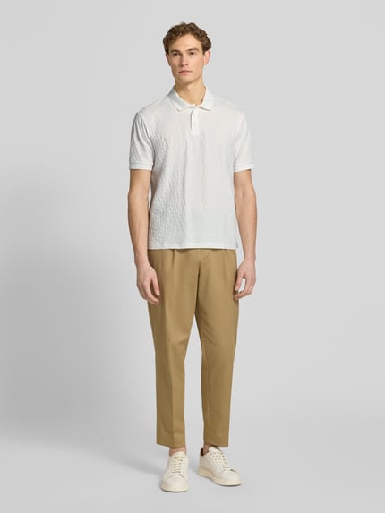 Mannenmodel draagt Regular Fit poloshirt met structuurpatroon van ARMANI EXCHANGE, puur katoen, knoopsluiting, ruglengte maat M 68 cm, geheellichaamsbeeld vooraanzicht.