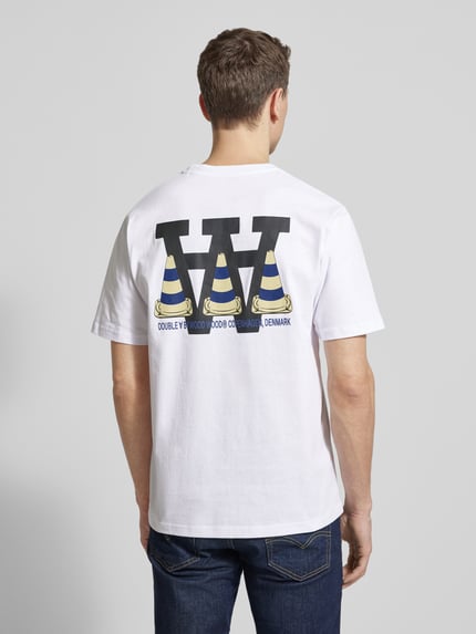 Männermodel trägt T-Shirt mit rückseitigem Motiv- und Logo-Print von Wood Wood, weiße Baumwolle, gerader Schnitt, Ganzkörperansicht Rückansicht.