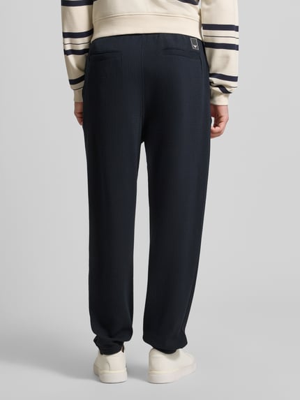 Männermodel trägt Hose mit Strukturmuster und Eingrifftaschen von Emporio Armani, Regular-Fit, Material-Mix mit Viskose-Anteil, dunkelblau, Gesäßtaschen, Bundweite 46 cm, Innenbeinlänge 73 cm, Ganzkörperansicht Rückansicht.