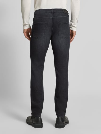 Männermodel trägt Slim Fit Jeans aus Baumwoll-Mix Modell 'Delaware' von BOSS in Dunkelblau, Herren Straight Fit Jeans, Ganzkörperansicht Rückansicht.