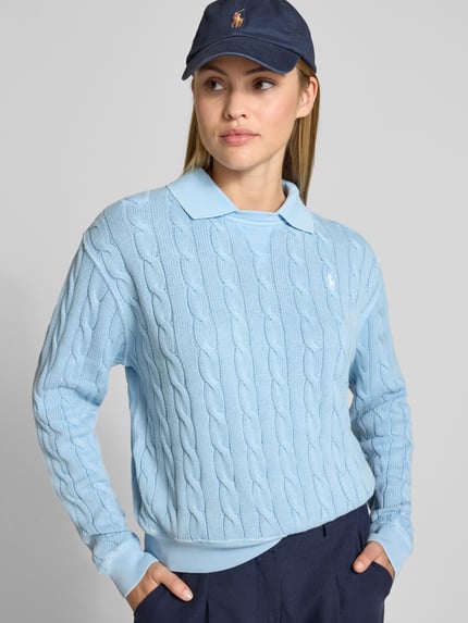 Frauenmodel trägt Regular Fit Pullover mit Polokragen von Polo Ralph Lauren in Hellblau mit Zopf-Strukturmuster aus Baumwolle, Nahaufnahme Oberkörper.
