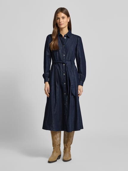 Modelka nosi Midikleid mit Druckknopfleiste von More & More z czystej bawełny, krój slim fit, kołnierzyk koszulowy, pasek w talii, długość pleców w rozmiarze 36: 117 cm, szerokość w rozmiarze 36: 47 cm, długość rękawa w rozmiarze 36: 65 cm, ciemnoniebieska tkanina o gładkiej fakturze, widok całej sylwetki od przodu