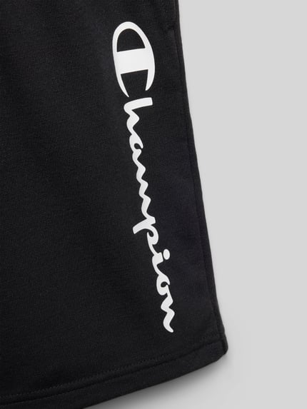 Produktfoto, Shorts mit Logo und elastischem Bund von CHAMPION, schwarzer Baumwoll-Mix, sichtbares weißes Logo, strukturierte Oberfläche.
