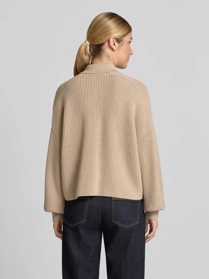 Frauenmodel trägt Strickjacke aus Schurwolle mit Pattentaschen von windsor., beige, strukturierte Oberfläche, Relaxed Fit, Rückenansicht, Ganzkörperansicht Rückansicht