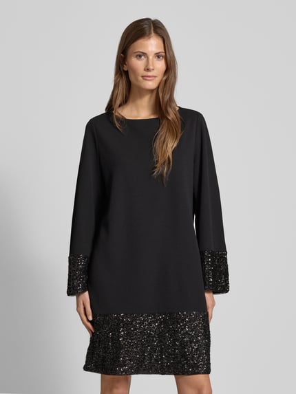 Vrouwenmodel draagt Relaxed Fit Mini-jurk met pailletten van s.Oliver BLACK LABEL, look: effen, pasvorm: relaxed fit, minilengte, boothals, paillettenapplicatie, zonder sluiting, lange mouw. Nahaufnahme Oberkörper.