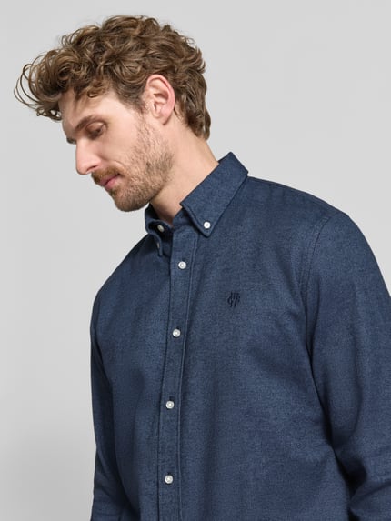 Männermodel trägt Regular Fit Freizeithemd aus reiner Baumwolle mit Label-Stitching von MCNEAL in Dunkelblau, Nahaufnahme Oberkörper. Herren Freizeithemd, Button-Down-Kragen, reine Baumwolle, Regular Fit, Rückenlänge 74 cm, Schulterbreite 50 cm, Ärmellänge 66 cm.