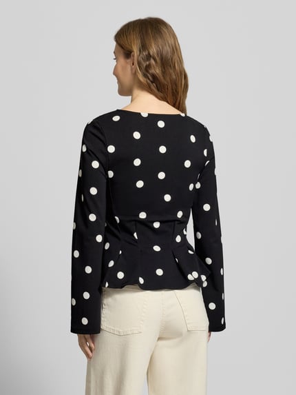 Frauenmodel trägt Longsleeve mit V-Ausschnitt von Gina Tricot in Schwarz mit weißen Punkten, taillierter Schnitt, Rückansicht, Ganzkörperansicht.