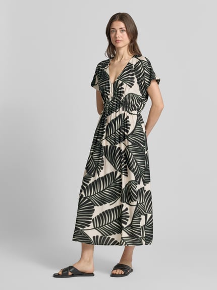 Frauenmodel trägt Midikleid aus Viskose-Mix mit floralem Allover-Print von Christian Berg Woman Selection, cremefarben mit schwarzen Blättern, taillierte Passform, V-Ausschnitt, kurzärmelig, Ganzkörperansicht von vorne.