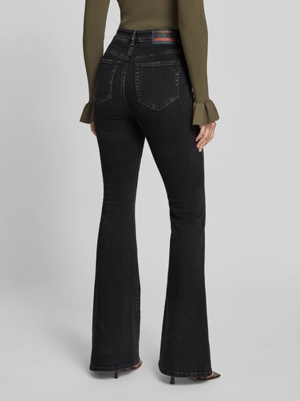 Frauenmodel trägt Flared Fit Jeans mit Logo-Detail von Diesel aus schwarzem Baumwoll-Mix, 5-Pocket-Design, feine Struktur, Ganzkörperansicht Rückansicht.